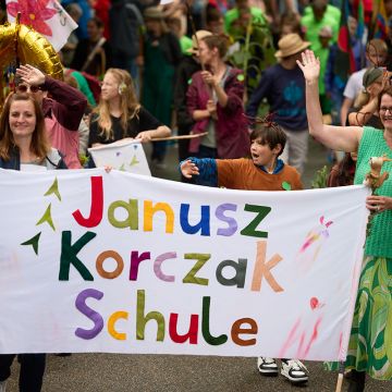 Die Schulleitung und eine Lehrkraft tragen das Schulbanner beim Umzug.